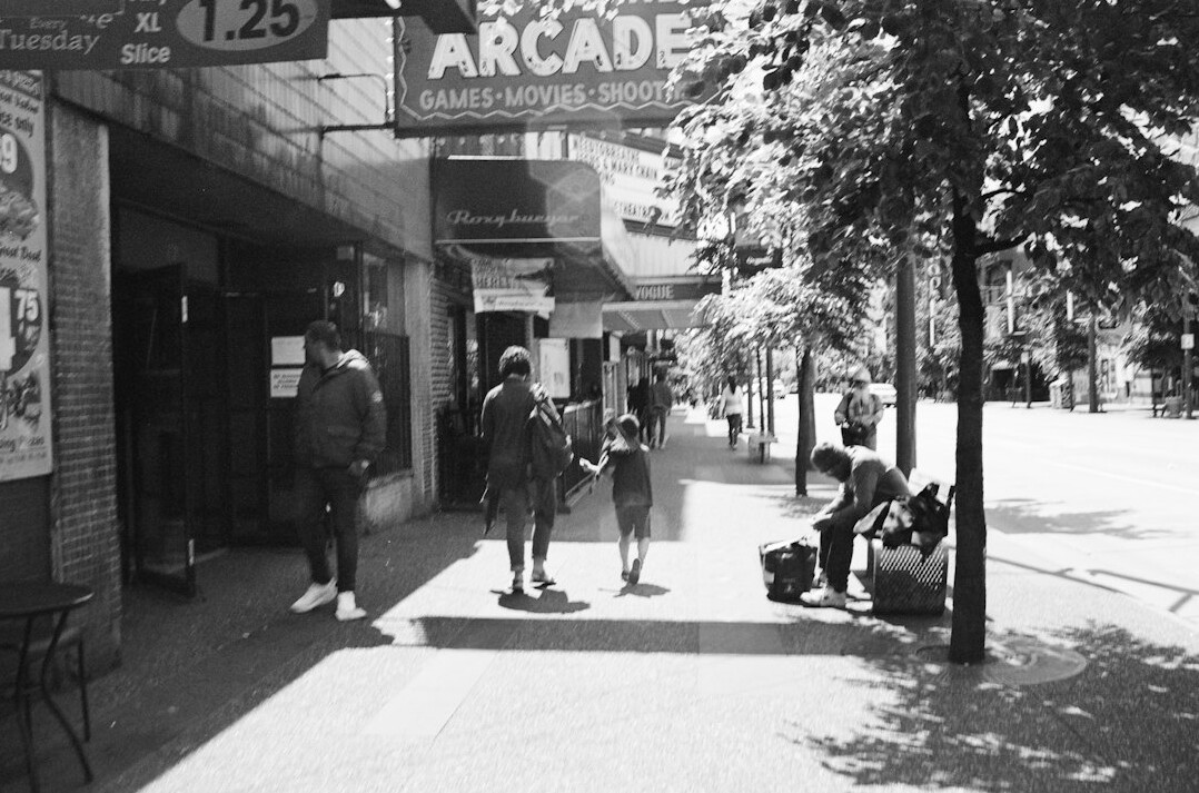 Indigenous Canadian street photographer holding a camera on a city sidewalk